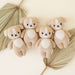 Four knitted teddy bears with white hearts on a neutral background