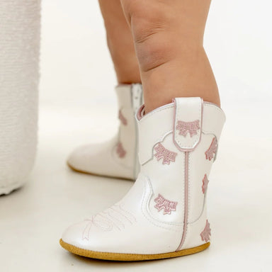 White boots with pink floral patterns worn by a child on a light background