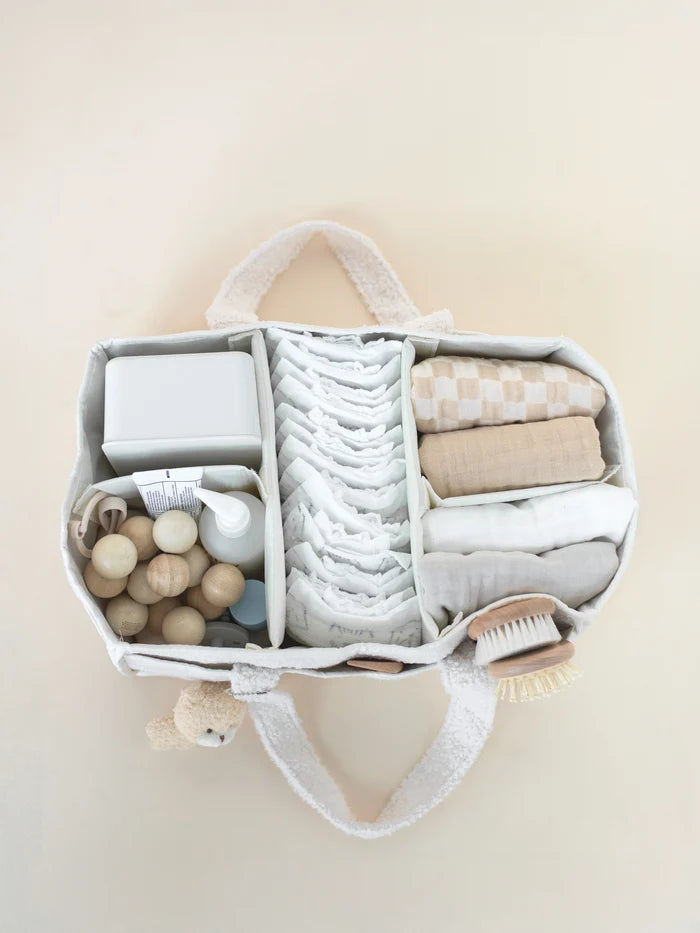 Organized diaper bag with baby items on a beige background