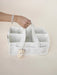 White storage caddy with a teddy bear toy held by a hand on a beige background