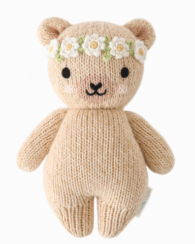 Knitted teddy bear with a flower crown on a white background