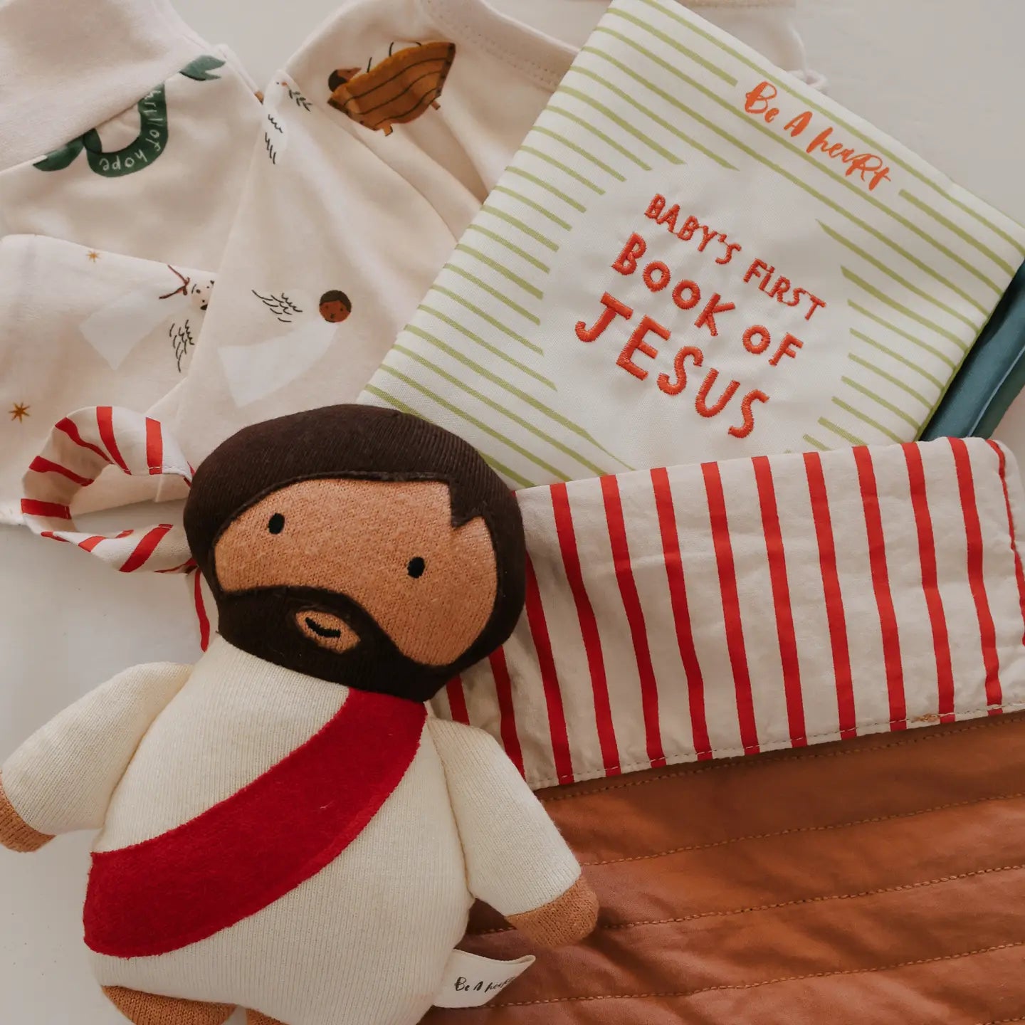 Baby's first book of Jesus with a soft toy and striped blanket on a textured surface