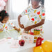 Two children in matching outfits with school-themed designs sitting at a table with educational materials.