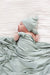 Newborn baby wrapped in a light green blanket and wearing a matching hat on a white background