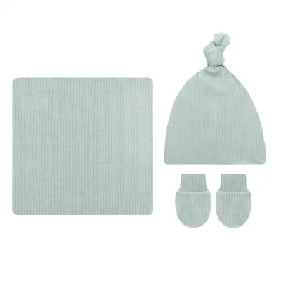 A baby knit gift set in a pale mint green ribbed fabric, including a square blanket, a knotted beanie hat, and a pair of mittens, arranged on a plain white background.
