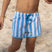 Blue and white striped swim shorts on a sandy background