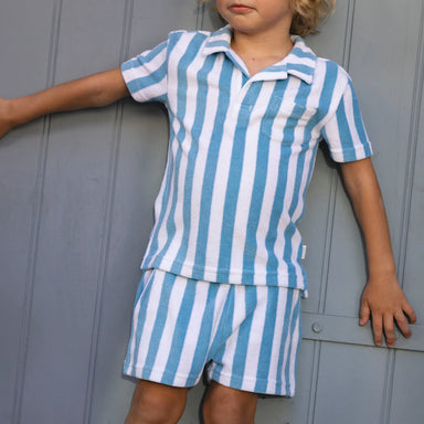 Child wearing a blue and white striped outfit against a gray background