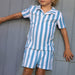 Child wearing a blue and white striped outfit against a gray background