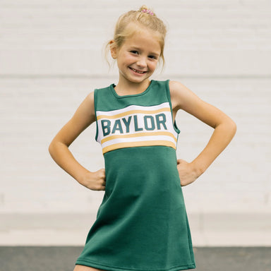 Young girl wearing a green 'Baylor' dress against a plain background