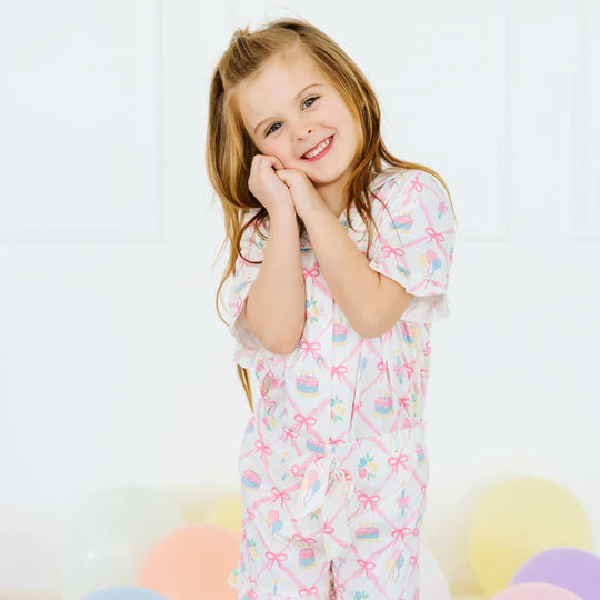 Young girl wearing a colorful pajama set with bows and patterns on a white background