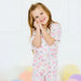 Young girl wearing a colorful pajama set with bows and patterns on a white background