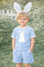 Child wearing a light blue outfit with a bunny design and bunny ears outdoors.