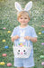 Child wearing bunny ears and a colorful Easter basket in a grassy area
