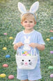 Child wearing bunny ears and a colorful Easter basket in a grassy area