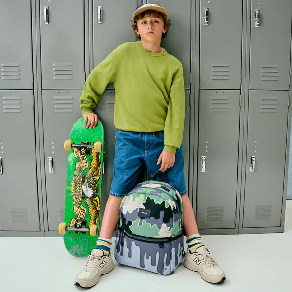 Boyd holding a skate board and a Camo Kanes Double Pocket Backpack