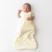 Newborn baby wrapped in a yellow sleep bag on a white background