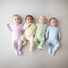 Four babies wearing pastel-colored onesies on a neutral background