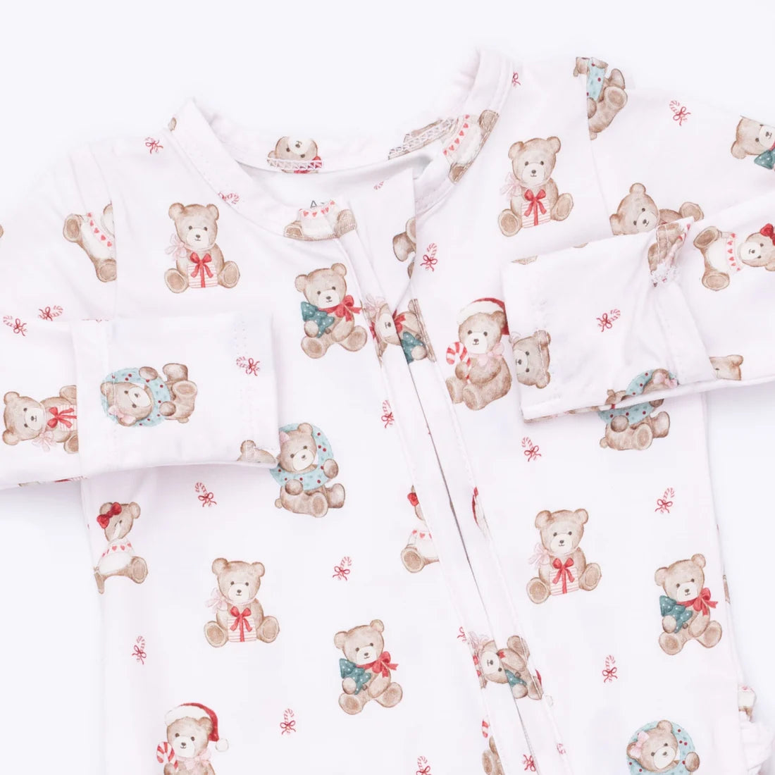 A baby long-sleeve footed sleeper in white with a repeating teddy bear print in muted red, blue, and beige.