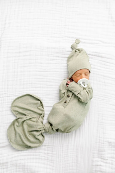Newborn baby wrapped in a green swaddle with matching hat on a white background