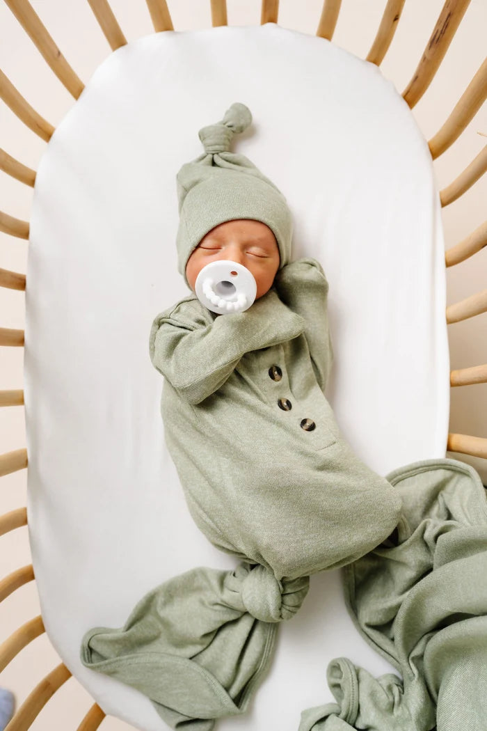 Newborn baby wrapped in a green outfit with a matching hat, sleeping peacefully.