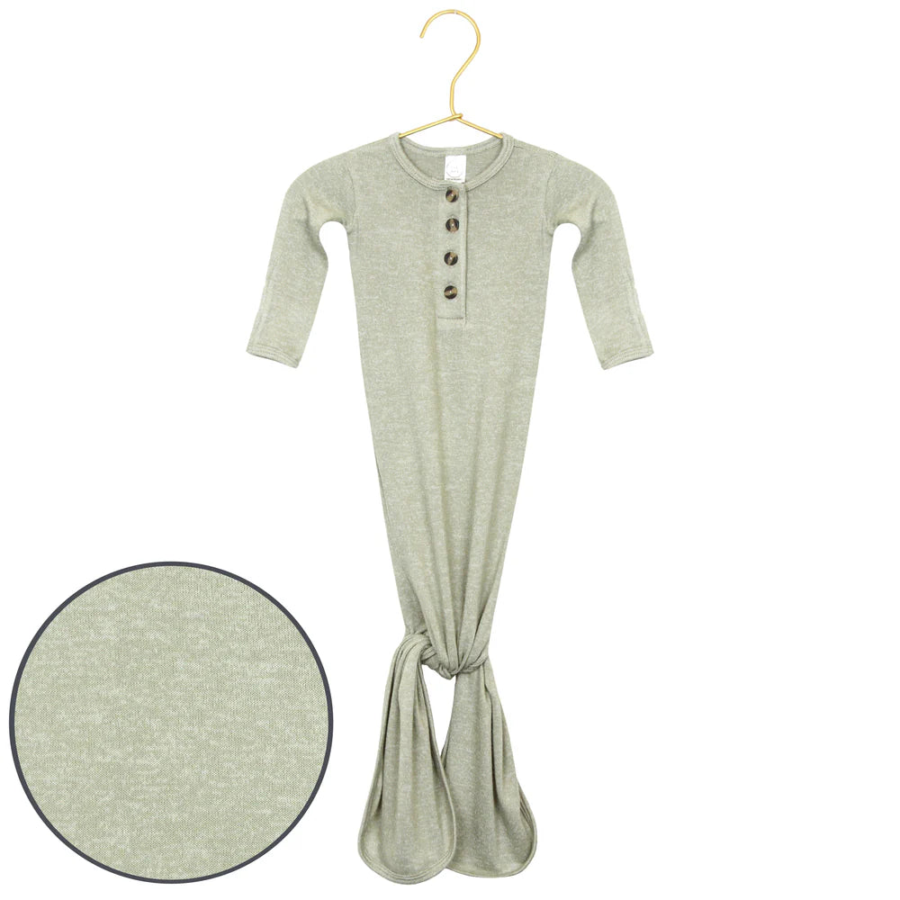 Green baby onesie with buttons on a hanger against a white background