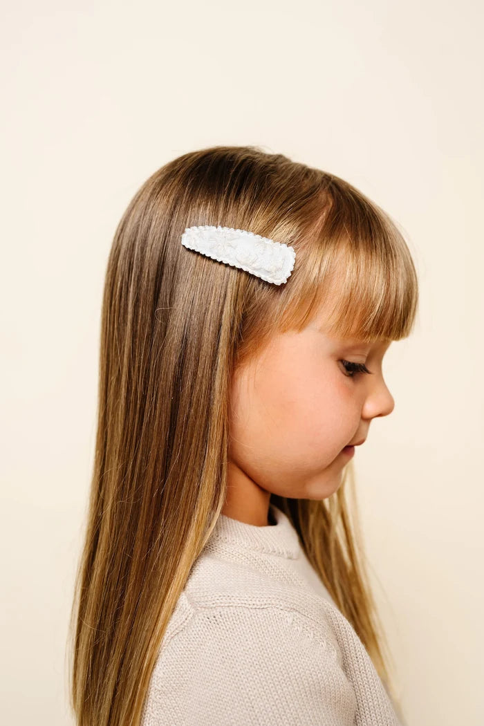 Young girl with a decorative hair clip on a plain background