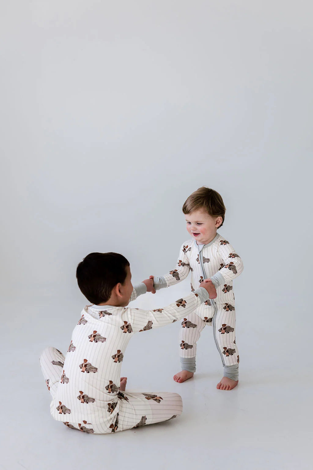 Two children in matching pajamas playing on a plain background