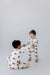 Two children in matching pajamas playing on a plain background