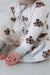 Baby wearing a onesie with teddy bear and car patterns on a light background