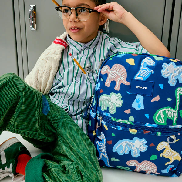 Boy sitting next to a Dino Fossils Kane Backpack