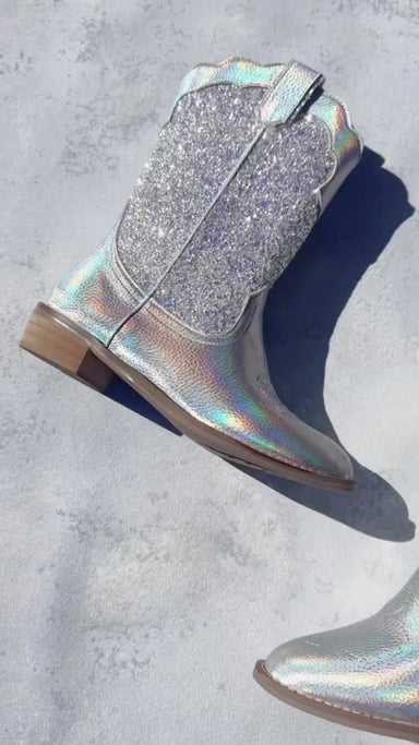 Holographic glittery boot on a concrete surface