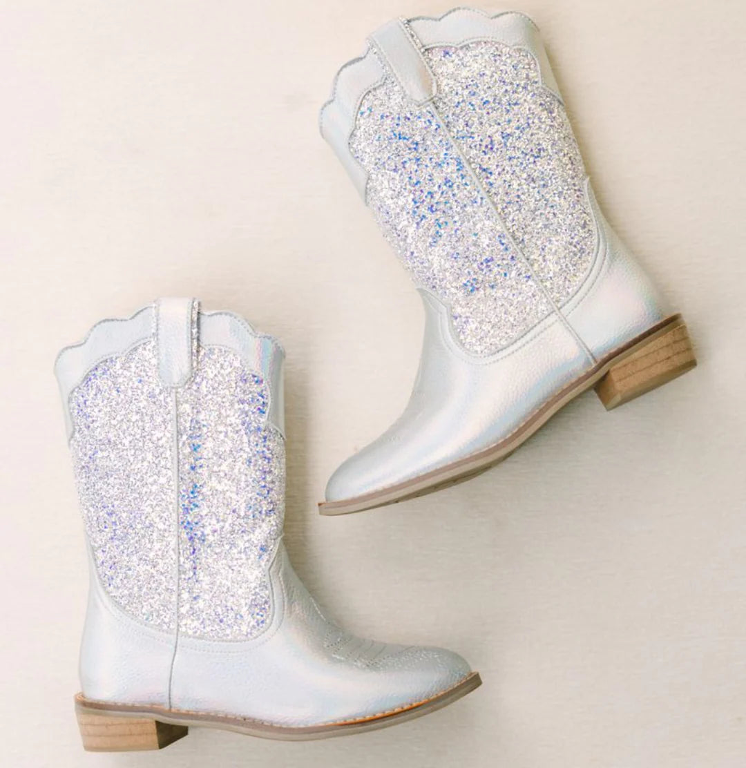 Pair of glittery silver cowboy boots on a beige background