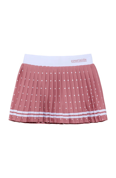 A pleated pink tennis skirt with white polka dots, featuring a white waistband with the brand name 'courtside' printed on it, set against a plain white background.