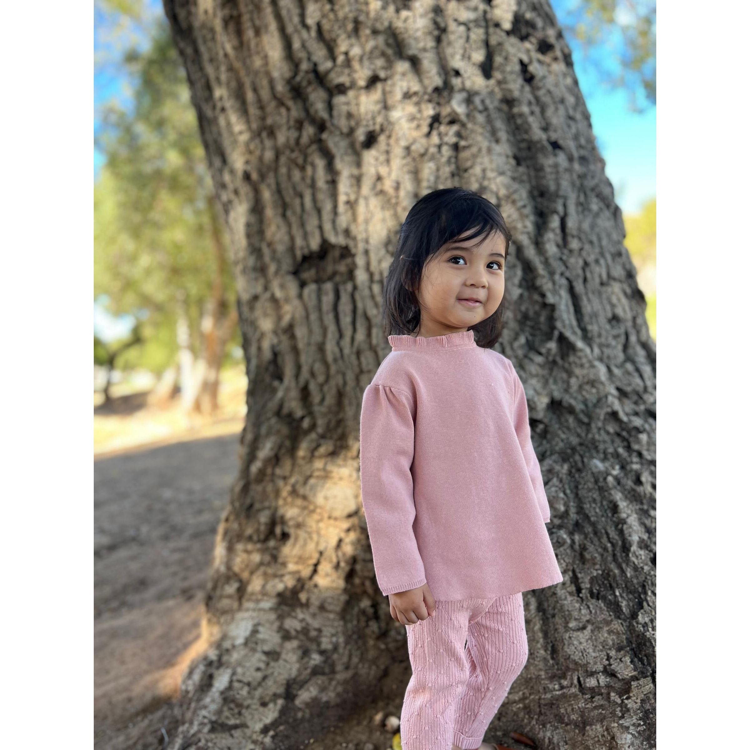 girl wearing long sleeve dusty pink sweater with ruffle detail at the neck