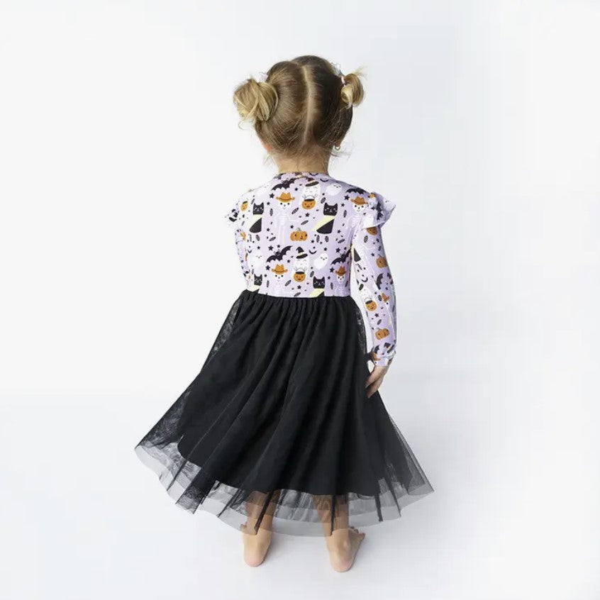 back view of girl wearing long sleeve purple spooky cute print dress with black tulle skirt