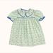 A light green baby dress with a small rodeo pattern, featuring a Peter Pan collar with blue trim, short puff sleeves with blue trim, and a smocked chest detail, shown flat on a cream background.