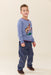 Young boy wearing a blue Pink Chicken sweater with a rodeo horse design and navy pants with western details in a studio setting