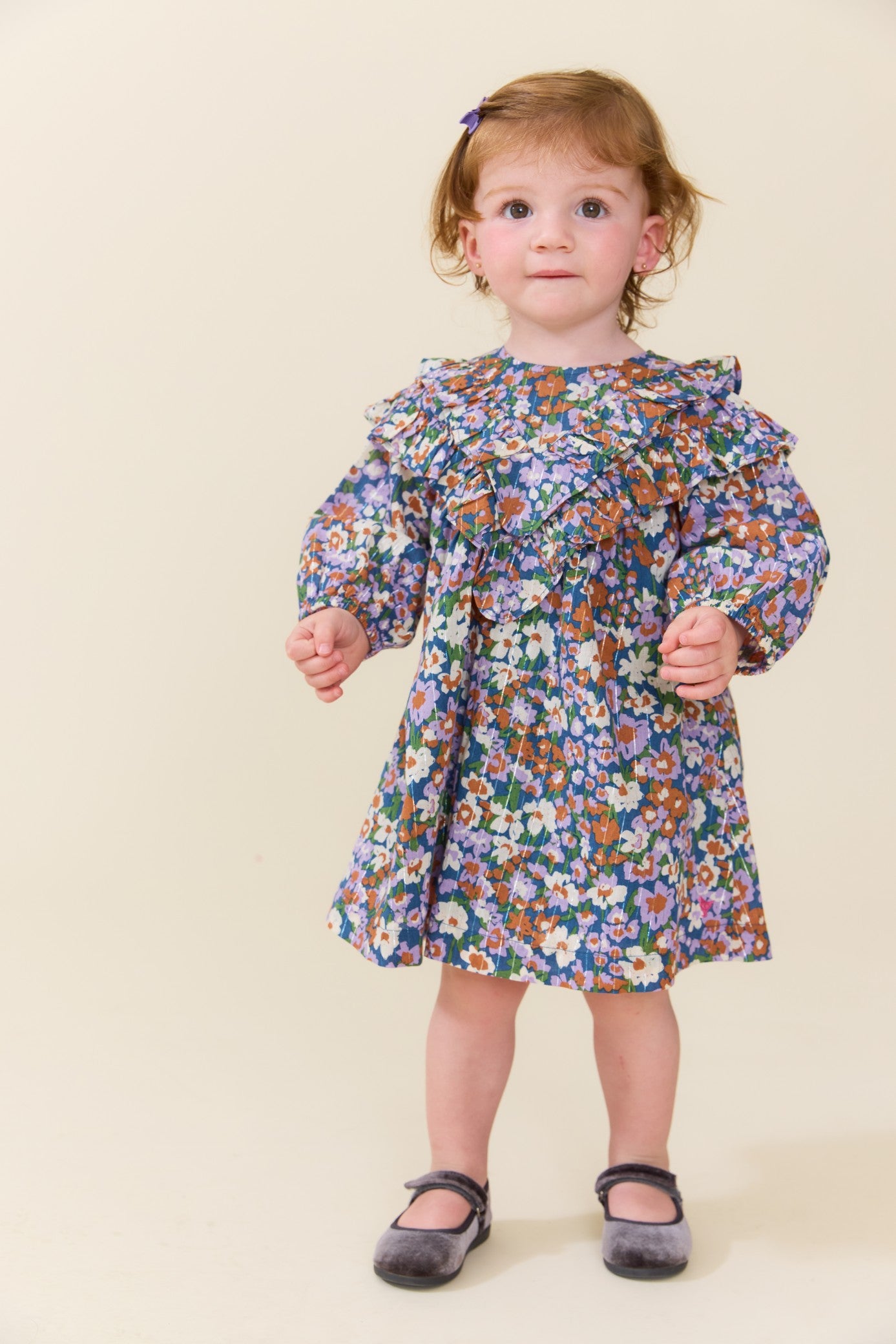Toddler girl wearing a blue floral long sleeve dress with a gathered skirt and ruffled neckline styled with Mary Jane shoes from Pink Chicken