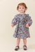 Toddler girl wearing a blue floral long sleeve dress with a gathered skirt and ruffled neckline styled with Mary Jane shoes from Pink Chicken