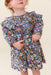 Young girl wearing a blue floral dress with a ruffled collar and puff sleeves from Pink Chicken for stylish everyday occasions
