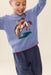 Smiling child wearing a blue knit sweater with a bucking horse design and red trim paired with navy pants from Pink Chicken’s Oliver Broncos collection