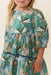 Young girl wearing a Pink Chicken green Maribelle dress with colorful butterfly print gathered tiers and short sleeves