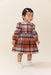 Toddler girl wearing a multicolor plaid long sleeve dress with a gathered skirt and white shoes from Pink Chicken