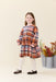 Young girl modeling a Pink Chicken plaid long sleeve dress with white tights and leopard print shoes in a bright studio setting