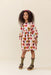 Young girl wearing a Pink Chicken long sleeve dress with colorful harvest heart print styled with a pink headband ribbed socks and brown sandals
