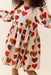Child wearing a pink dress with colorful heart print and puff sleeves by Pink Chicken