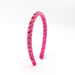 Pink headband with gold accents on a white background
