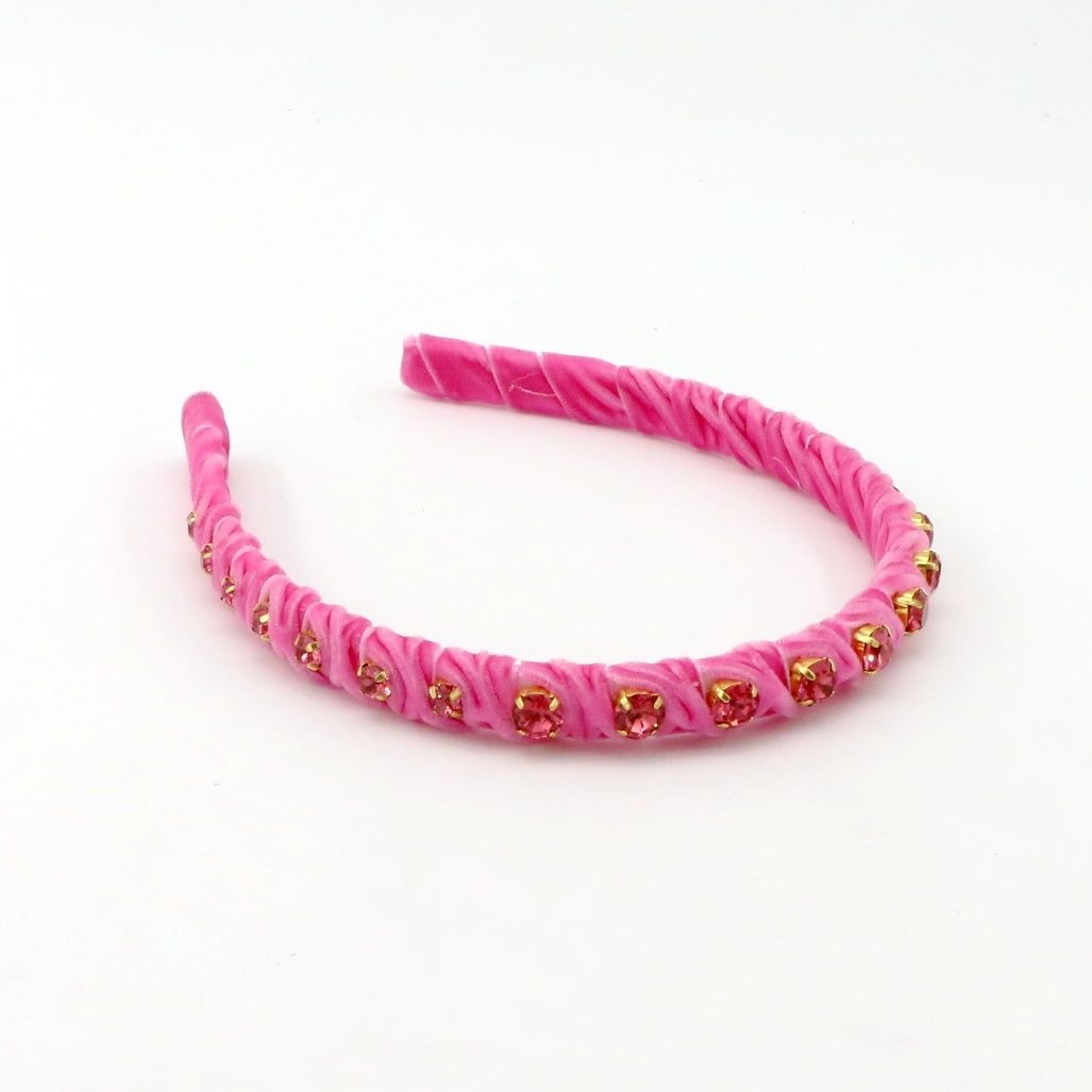 A pink braided headband embellished with small gold and pink rhinestones, displayed on a clean white background.