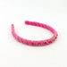 A pink braided headband embellished with small gold and pink rhinestones, displayed on a clean white background.