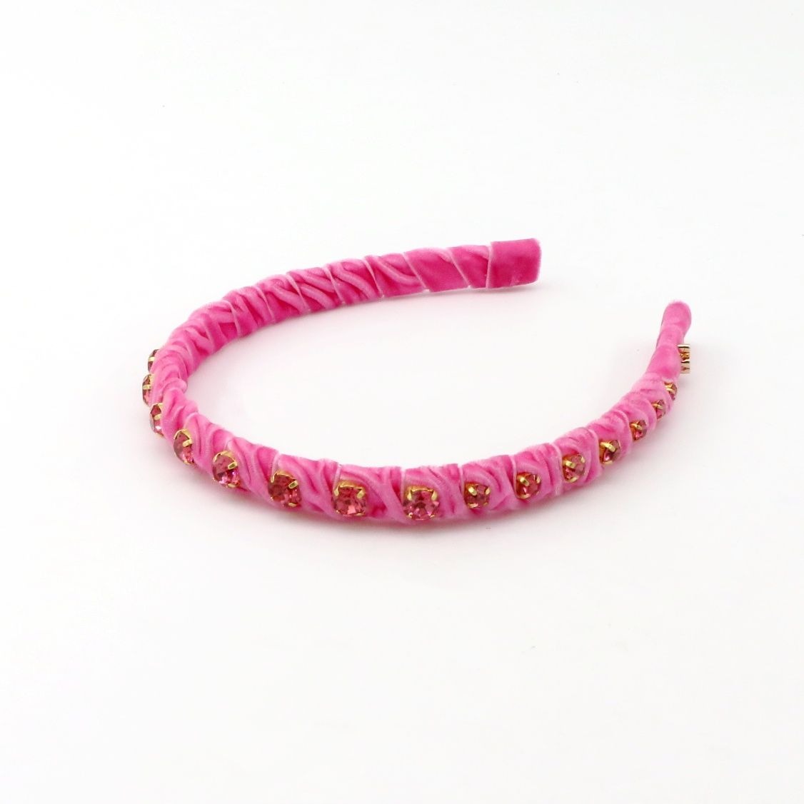 A pink velvet headband with a textured, ruched design and small gold rhinestone accents, displayed on a clean white background.